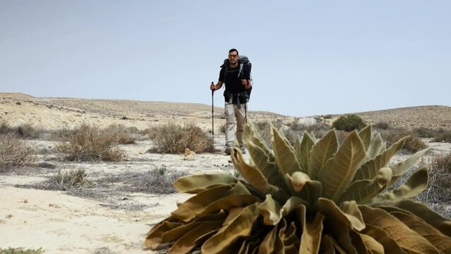 Slow motion of a man hiking through a dry desolate desolate landscape