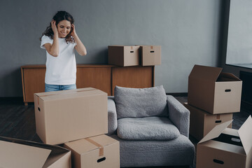 Happy young spanish woman relocates alone. Girl is packing cardboard boxes. Mortgage concept.