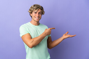 English man over isolated purple background holding copyspace imaginary on the palm to insert an ad