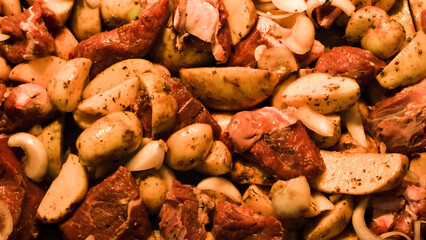 Top close up view raw meat with potatoes in baking tray before cooking spiced with herbs