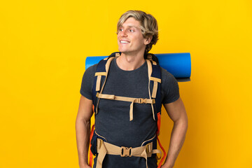 Young mountaineer man over isolated yellow background looking to the side and smiling