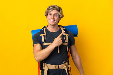 Young mountaineer man over isolated yellow background pointing to the side to present a product