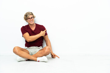 Fototapeta premium Young English man sitting on the floor pointing back