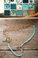 handmade jewelry necklace  and different azure beads and chrystals in box around old style wooden...
