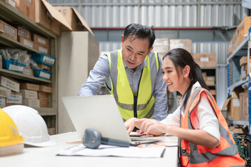 Female worker discussing with senior male manager using laptop checking products in stock inventory at warehouse office