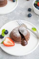 Chocolate fondant lava cake with fresh berries on a plate on a gray background.