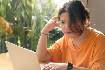 Disappointed Asian businesswoman, female trader using computer laptop for stock investing,...