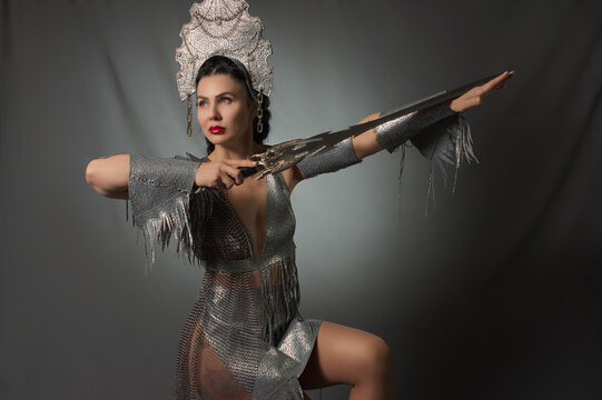 female warrior with a sword in her hands and a crown on her head. Studio photography. grey background.