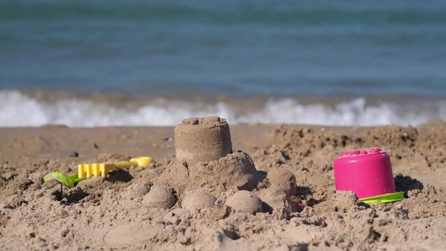 Children beach toys - buckets, spade and shovel on sand on sunny day. Children built sand castle near sea during summer vacation holiday. Happy family have fun on tropical sea beach resort