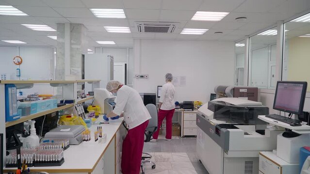 Doctors Use Medical Analysis Equipment In Modern Medical Blood Test Laboratory. Medical Specialists Examine Biochemistry Analysis Results In Laboratory. Medical Analysis Machine In Clinic Laboratory