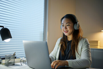 Asian female wearing headphone working at home.
