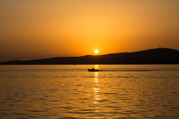 View of a small boat, Aegean sea and landscape at sunset captured in Ayvalik area of Turkey in summer.