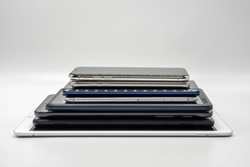 Stack of cell phones and pads on white background
