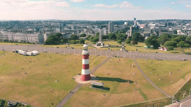 Aerial drone shot of a red and white striped lighthouse on the coast in Plymouth, UK