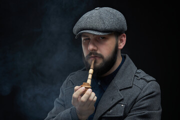 Bearded guy in a coat on a dark smoky background