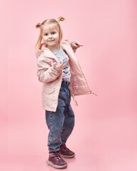 a child in a jacket on a pink background.