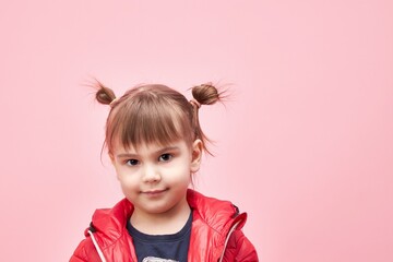 a child in a jacket on a pink background.