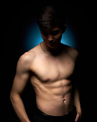 Fototapeta premium a healthy athletic teenager shows off his body against a dark background, the concept of proper nutrition