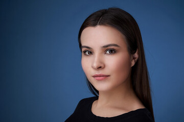 Fototapeta premium portrait of a young brunette lady on a dark blue background.
