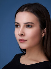 Naklejka premium portrait of a young brunette lady on a dark blue background.