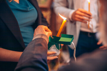 A priest is putting a baby's cut hair in a box for safe keeping at an orthodox baptism. People are...