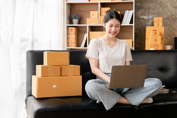 Portrait of a small business startup, SME owner, female entrepreneur, working, unboxing, checking orders online. To prepare to pack boxes for sale to SME customers online business ideas