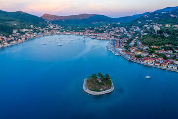 Vathy harbor with sailboats and catamarans anchored on the shore of the village of Ithaca Greece. Small marina Limani Vathy with a small island at the entrance. Sunset over the harbour. Beautiful Sea 