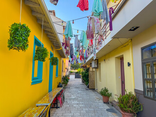 Beautiful colored and narrow street in Lefkada Greece covered with colorful ornaments above. Cozy street in the historic center. Brightly colored house walls on the street. Walking around . 