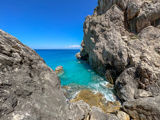 Mediterranean sea coastline with waves crashing against the cliffs on the shoreline. Turquoise water in the ocean with waves crashing against the rocks. Exotic waters on desert islands. Big rocks