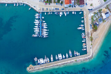 Aerial top-down view of docked sailboats. Top down view of yachts in the marina. Sailboats and regular Boats moured in Palairos Marina Greece. Sailboats and catamarans anchored in the harbour.