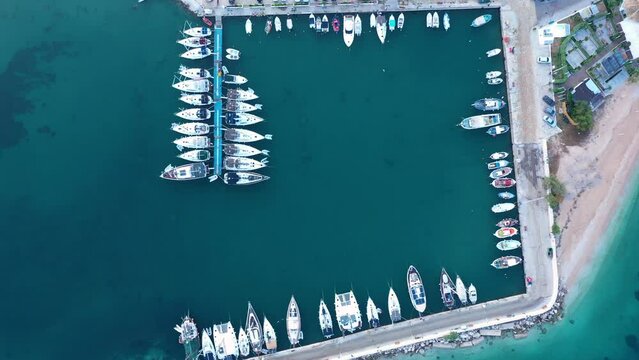 Aerial top-down view of docked sailboats. Top down view of yachts in the marina. Sailboats and regular Boats moured in Palairos Marina Greece. Sailboats and catamarans anchored in the harbour.