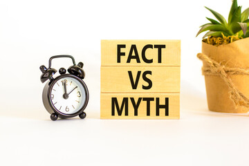 Fact vs myth symbol. Concept words Fact vs myth on wooden blocks on a beautiful white table white background. Black alarm clock. Business, finacial and fact vs myth concept. Copy space.