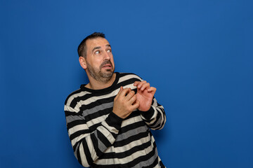Fototapeta premium Hispanic bearded man tremendously scared by something next to him, copy space. Isolated on blue studio background.