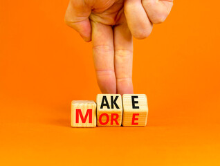 Make more symbol. Concept words Make more on wooden cubes. Businessman hand. Beautiful orange table orange background. Business, motivational quotes and Make more concept. Copy space.