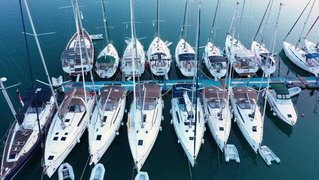 Aerial top-down view of docked sailboats. Top down view of yachts in the marina. Sailboats and regular Boats moured in Palairos Marina Greece. Sailboats and catamarans anchored in the harbour.
