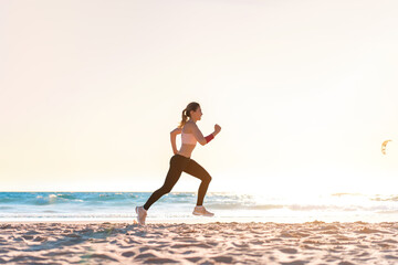 Fototapeta na wymiar Sporty blonde woman running ocean beach. Young caucasian female exercising outdoors running seashore. Concept of healthy running and outdoors exercise.