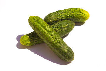 three green cucumbers lie on a white background