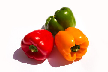 three different colored peppers: red, green and yellow peppers lie on a white background