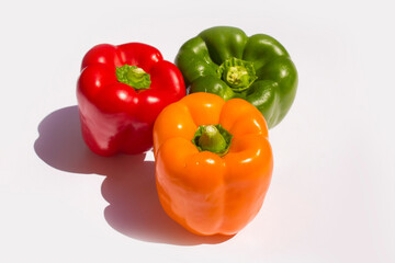 three different colored peppers: red, green and yellow peppers lie on a white background