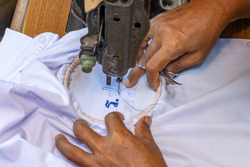 Embroidering Thai numbers on a student's shirt on an old sewing machine
