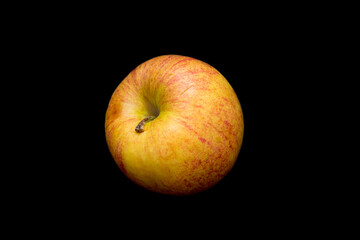 yellow organic apple lies on a black background