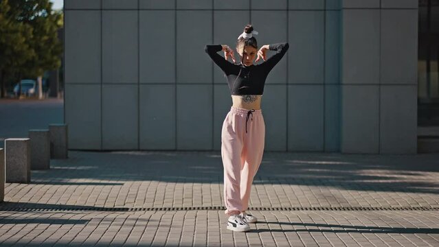 Young woman enjoys performing vogue dance on empty street