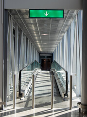 The entrance into an empty corridor with a moving sidewalk lit by the sun