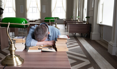 Senior man falls asleep over a textbook, he is sitting at a table that is littered with teaching materials. Portrait of caucasian Senior man working with book in public library. education concept