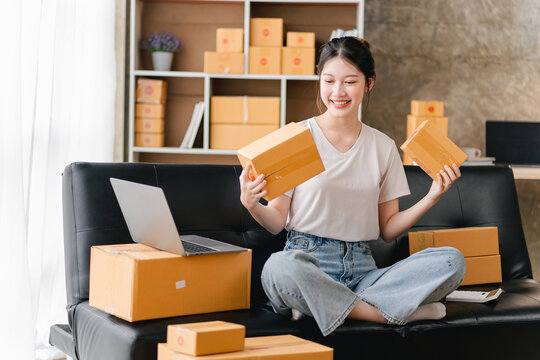 Portrait of a small business startup, SME owner, female entrepreneur, working, unboxing, checking orders online. To prepare to pack boxes for sale to SME customers online business ideas