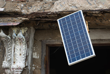 A solar panel hangs in the window of an old unmaintained building