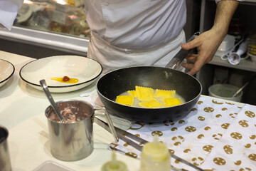 Chef of a Restaurant who is going to Plate the Freshly Cooked Italian Pasta Specialty - Dishes already Stuffed with Toppings