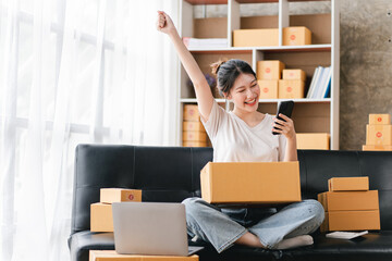 Portrait of a small business startup, SME owner, female entrepreneur Excited about the sales that exceeded the target. check work order online To prepare to pack boxes for sale to SME customers online
