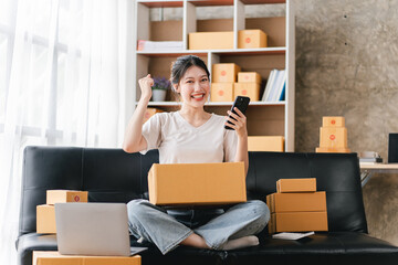 Portrait of a small business startup, SME owner, female entrepreneur Excited about the sales that exceeded the target. check work order online To prepare to pack boxes for sale to SME customers online