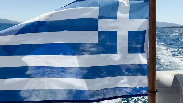 Greek flag waving from behind of a catamaran sailing in the sea. Flag of Greece Waving in the wind. Sailing in Greece. 